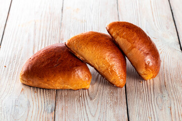 Freshly baked tasty bun on a white wooden table. Tasty baked goods straight from the bakery. White background.