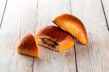 Freshly baked tasty bun on a white wooden table. Tasty baked goods straight from the bakery. White background.