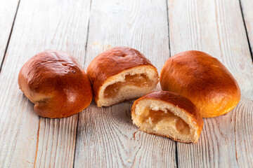 Freshly baked tasty bun on a white wooden table. Tasty baked goods straight from the bakery. White background.