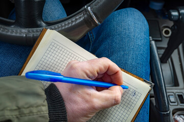 an open paper notebook, a book for notes, a journal for notes lies on the driver lap inside the...