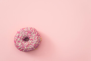 Pink background with one decorated doughnut; space for text
