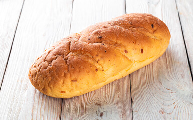 Freshly baked tasty bun on a white wooden table. Tasty baked goods straight from the bakery. White background.