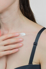 A woman applies moisturizer to her collarbone. Skin care. Moisturizing the skin in winter