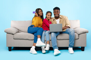 Fototapeta na wymiar Happy black family using laptop computer and credit card
