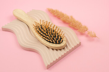 Wooden hairbrush on pink background with geometric shapes