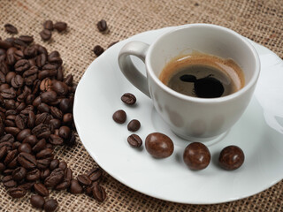Tazzina di caffè e caffè in grani con cioccolatini nel piattino