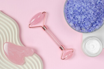 Spa composition with selective focus. Pink jade facial massager on pink background