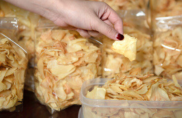 Fried durian chips. Woman's hand holding crispy durian chips, Famous durian products from Thailand. Durian chips fried and whole is snack of Thailand.