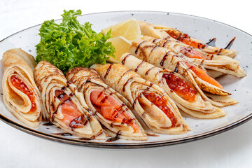 Pancakes stuffed with red caviar and salmon.  Russian dish. Isolated on a white background