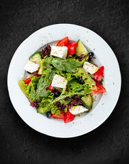 Greek salad with fresh vegetables and feta cheese. Isolated on a black background