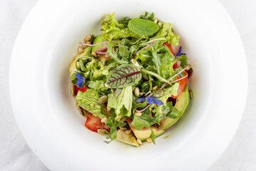 Salad with avocado and pine nuts. Isolated on a white background.