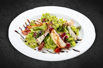 Salad with chicken fillet, dor blue cheese and pistachios. Isolated on a black background.