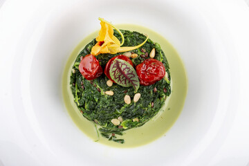 Stewed spinach with pine nuts. Isolated on a white background.