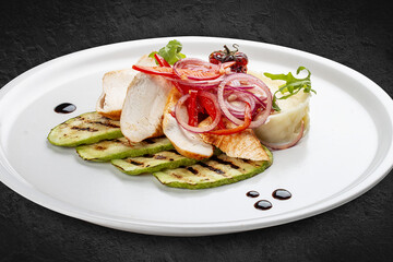 Baked chicken fillet on a pillow of mashed potatoes. Isolated on a black background.