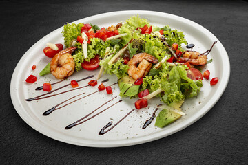 Salad with avocado and tiger prawns, seasoned with pesto sauce. Isolated on a black background.
