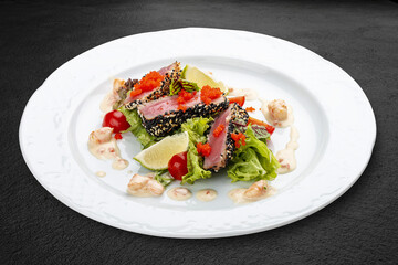 Tuna on a pillow of chuka with shrimp sauce . Isolated on a black background.
