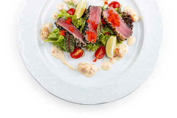 Tuna on a pillow of chuka with shrimp sauce . Isolated on a black background.