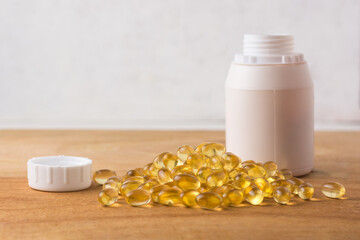 oil capsules, omega 3 and vitamin supplement on a wooden table top with the bottle, healthy lifestyle concept, with copy space for text, template