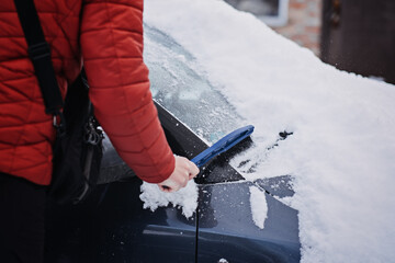 Man cleaning car from snow and ice with brush and scraper tool during snowfall. Winter emergency....