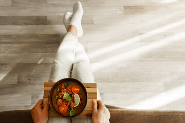 Woman holding a bowl of thick lentil soup with vegetables