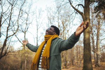 Black man breathing fresh air stretching arms in a park. Shot of a man standing outside with his...