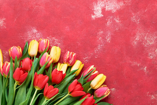 Red and yellow tulips bouquet on a bright red background. Holidays concept. Copy space, flat lay
