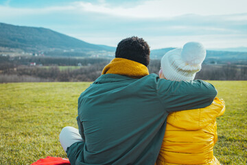 Couple is hugging and sitting close in the forest. Back view of Romantic Couple in love sitting on...