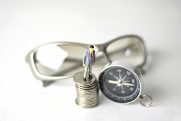 Obraz na płótnie Canvas Business man Figure miniature or small people,compass,glasses and money coin.Concept business investment.
