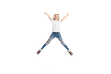 Dynamic portrait of little girl, kid in casual clothes jumping, having fun isolated on white studio background.