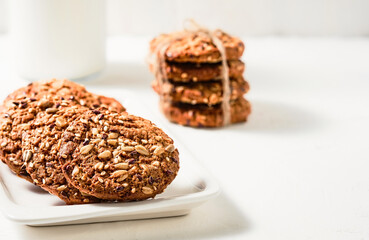 Homemade oatmeal cookies on a plate. The idea for breakfast is cookies and milk. Handicraft cookies with flax and sesame seeds on a white plate. Selective focus. Festive baked goods