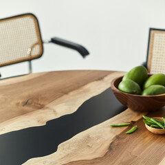 Minimalist composition on the design wooden table with fruits, nuts and stylish chair. Modern dining room. Template.