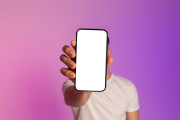 Unrecognizable millennial guy holding cellphone with empty white screen in front of his face in...