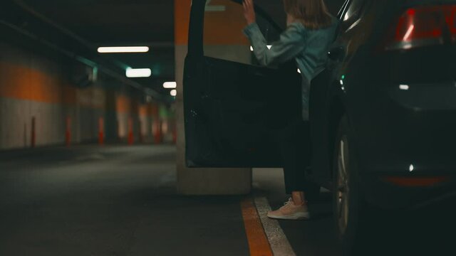 Woman locking her car with key in underground parking.