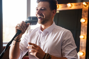 Young smiling man with microphone is singing at home