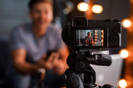 Bearded blogger sitting on a sofa is looking into a camera and smiling