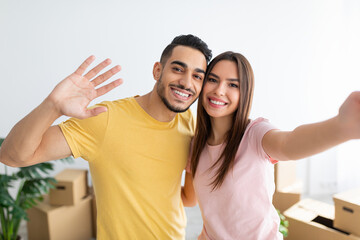 Beautiful Caucasian woman with her Arab husband taking selfie, moving to new house together