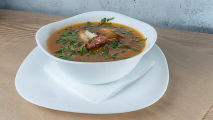 Traditional Russian soup Solyanka with beef, chicken, sausage, lemon, olives and pickled cucumber. Delicious hot lunch.
