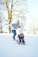 Mother and her cute little son having on a sledding hill