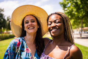 Portrait of two multiethnic friends smiling to the camera in summer outfit