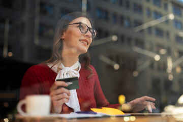 Happy woman using credit card to shopping online with tablet. Beautiful young woman drinking coffee in cafe..