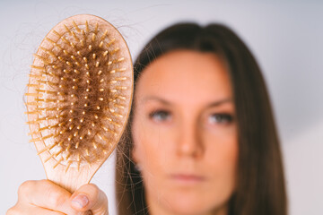 Woman showing hair brush with damaged hair. Hair loss problem. Bad hair falling out - obrazy, fototapety, plakaty