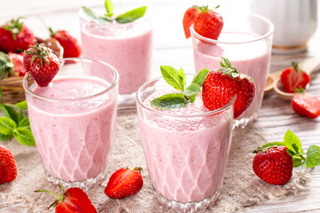 Glass of freshly made strawberry smoothie on wooden background. Healthy food and drink concept