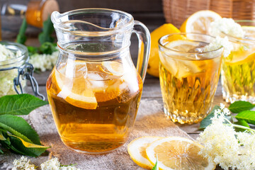 Jug of elderflower syrup and elderberry flowers on table