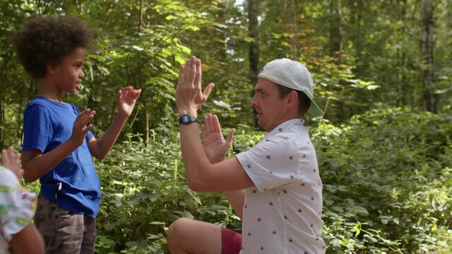 Male kindergarten teacher teaches children playing with hands in a urban playground. Lifestyle, outdoor. Patty Cake also known as Pat-A-Cake is one of the easiest hand-clapping games to start.