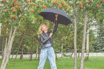 a beautiful girl with an umbrella among the trees with a rowan tree