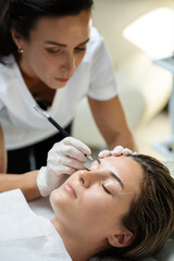 Obraz na płótnie Canvas Woman during professional eyebrow mapping procedure