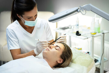Obraz na płótnie Canvas Woman during professional eyebrow mapping procedure