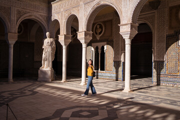young attractive Asian woman walking by monument in Seville - obrazy, fototapety, plakaty