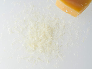 Whole and grated italian hard cheese Grana Padano or Parmesan isolated on white background. Delicious ingredient for pizza, sandwiches, salads. Front view.