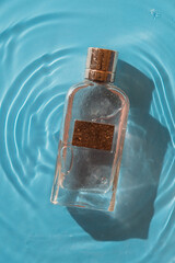 perfume bottle on a blue background in water, copy space